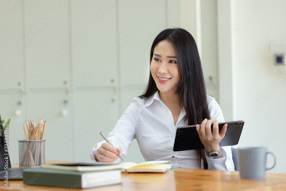 Happy asian young businesswoman using digital tablet sitting in office working space. Happy asian young businesswoman using digital tablet sitting in office working space.