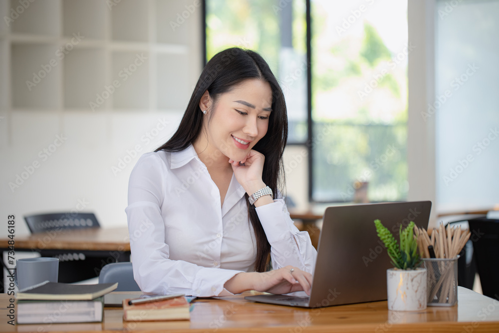 Happy asian young businesswoman using laptop at workplace. Happy asian young businesswoman using laptop at workplace.