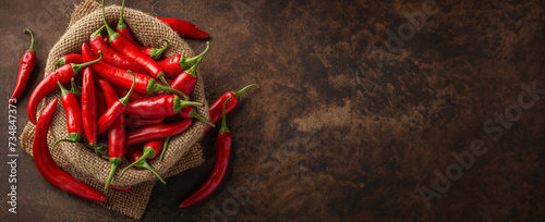 A bunch of red chili peppers in a burlap sack on brown background. With copy space