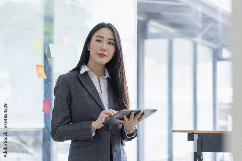 Happy asian young businesswoman using digital tablet standing in office office working space. Happy asian young businesswoman using digital tablet standing in office office working space.