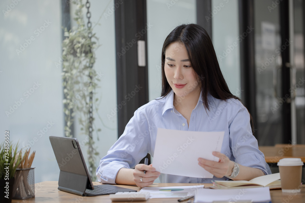 Happy asian accounting businesswoman working in office working space, Asian female employee using laptop at workplace. Happy asian accounting businesswoman working in office working space, Asian female employee using laptop at workplace.