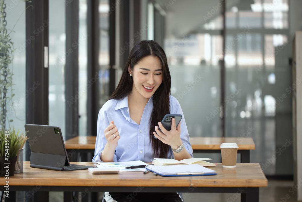 Happy asian young businesswoman excited with smartphone at workplace, Excited happy Asian woman. Happy asian young businesswoman excited with smartphone at workplace, Excited happy Asian woman.