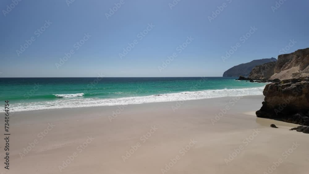 Al Fizayah hidden beach of Salalah in Oman. Local beach with camels grazing along the beach and mountains enhance the natural beauty of this popular destination of South Oman coast.