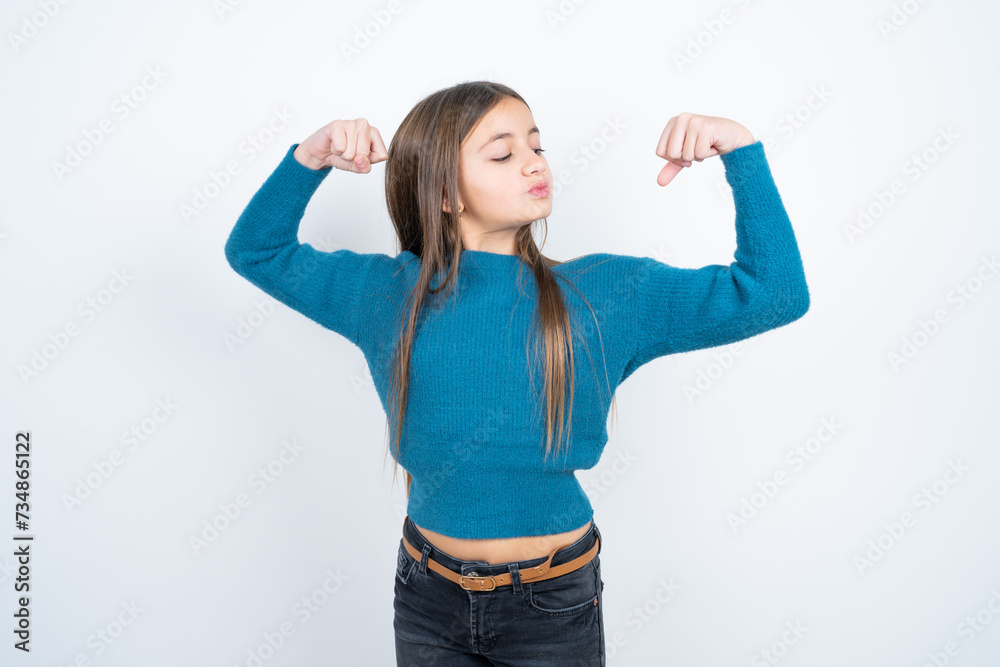 Young beautiful teen girl wearing blue T-shirt showing arms muscles smiling proud. Fitness concept. Young beautiful teen girl wearing blue T-shirt showing arms muscles smiling proud. Fitness concept.