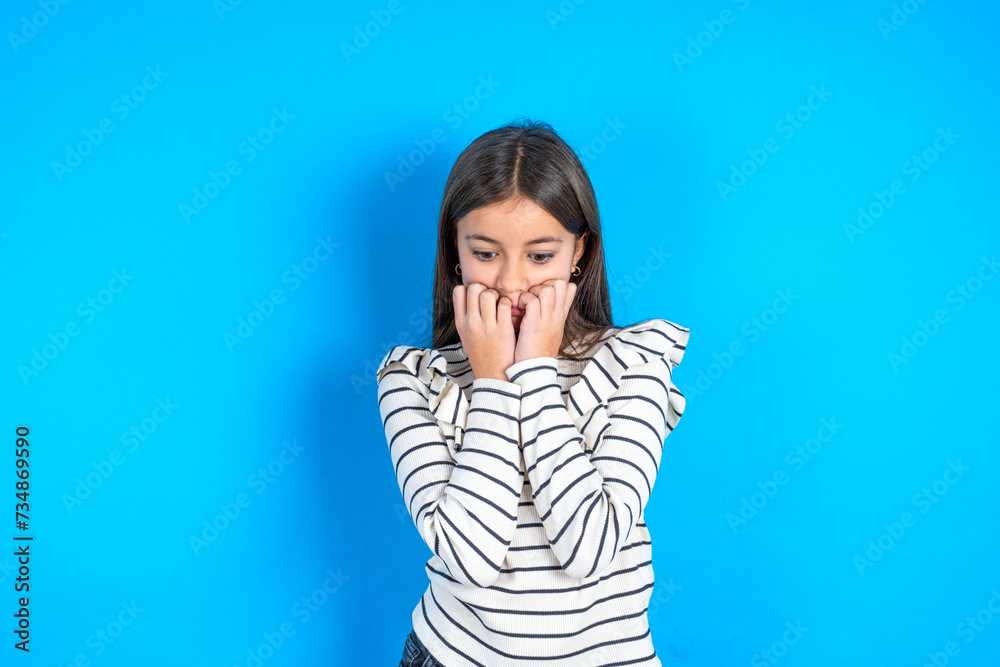 Fearful Young beautiful teen girl wearing striped T-shirt keeps hands near mouth, feels frightened and scared,  has a phobia,  Shock and frighted concept.