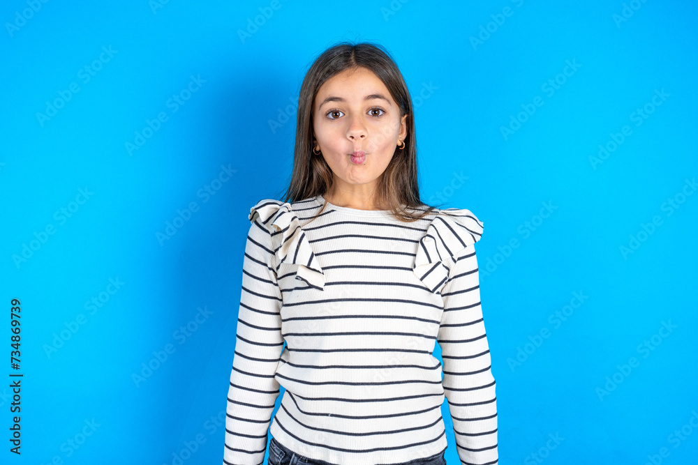 Shot of pleasant looking Young beautiful teen girl wearing striped T-shirt , pouts lips, looks at camera, Human facial expressions Shot of pleasant looking Young beautiful teen girl wearing striped T-shirt , pouts lips, looks at camera, Human facial expressions