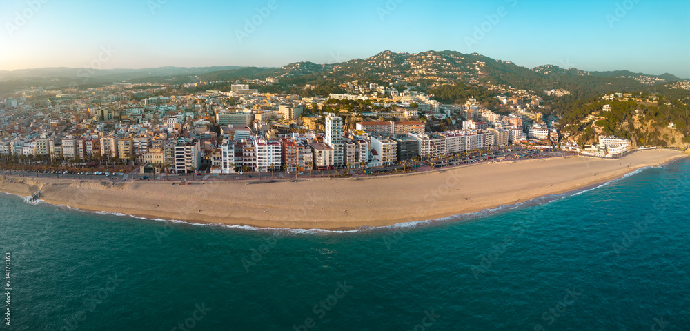 Panoramic aerial view of Lloret del Mar City. Mediterranean coastal town in Catalonia, Spain. One of the most popular Costa Brava beaches. Panoramic view of all region. Sunset warm colours.