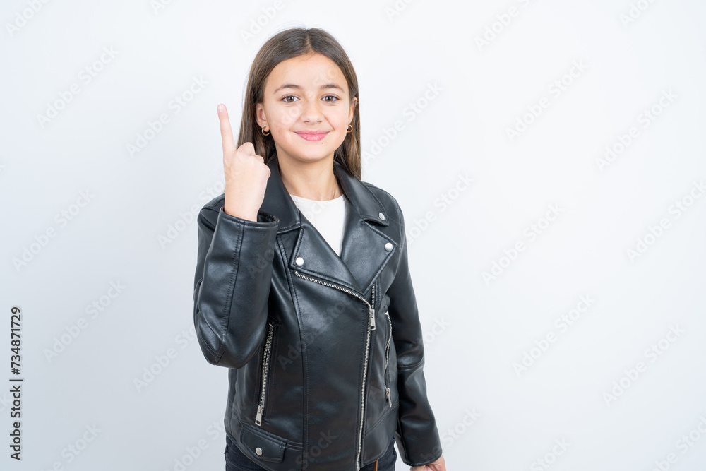 Young beautiful teen girl wearing biker jacket smiling and looking friendly, showing number one or first with hand forward, counting down Young beautiful teen girl wearing biker jacket smiling and looking friendly, showing number one or first with hand forward, counting down