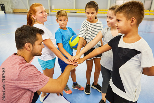 Students stacking hands with teacher in gym class photo