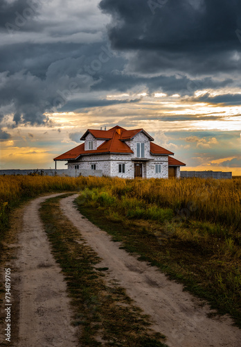 House in the field at sunset under cloudy sky