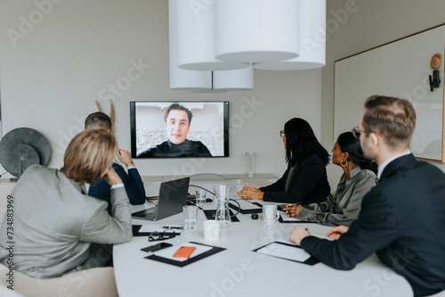 Multiracial colleagues discussing strategy through video conference in board room photo