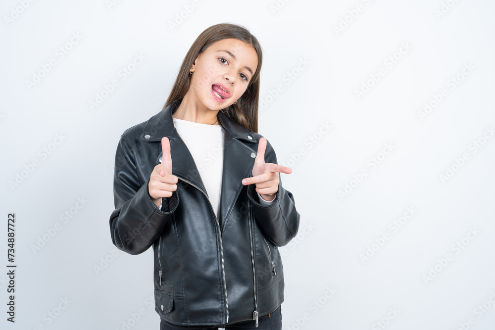 beautiful kid girl wearing biker jacket over white background directs fingers at camera selects someone. I recommend you. Best choice beautiful kid girl wearing biker jacket over white background directs fingers at camera selects someone. I recommend you. Best choice