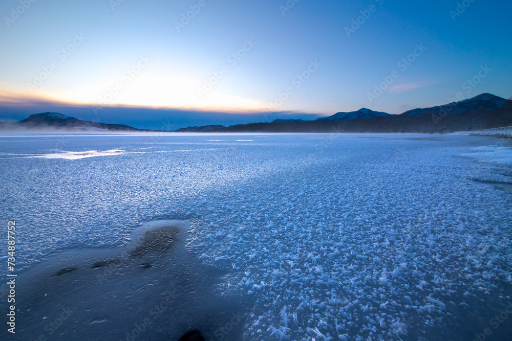 氷に覆われた冬の湖の夜明け。日本の北海道の屈斜路湖。雄大な自然の背景。