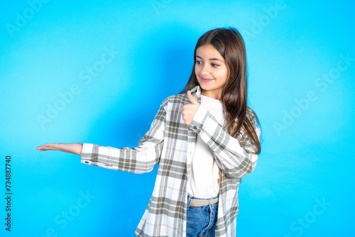 Beautiful kid girl wearing plaid shirt Showing palm hand and doing ok gesture with thumbs up, smiling happy and cheerful.