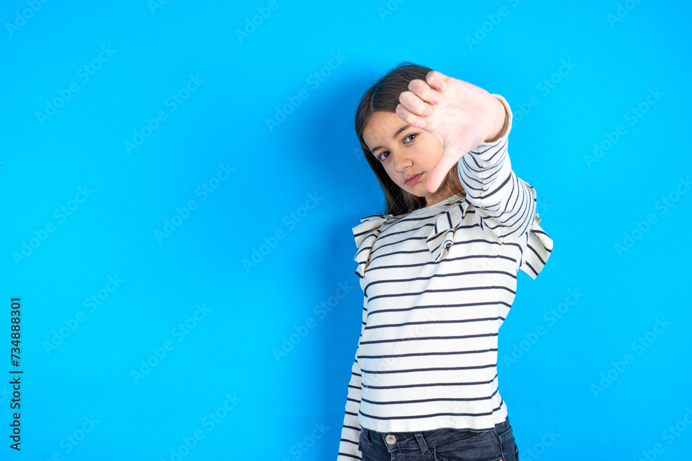 beautiful kid girl wearing  striped T-shirt feeling angry, annoyed, disappointed or displeased, showing thumbs down with a serious look
