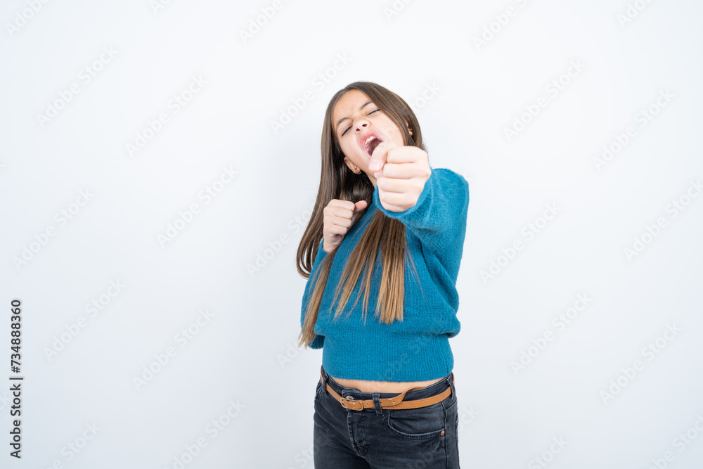 beautiful kid girl wearing blue sweater Punching fist to fight, aggressive and angry attack, threat and violence beautiful kid girl wearing blue sweater Punching fist to fight, aggressive and angry attack, threat and violence