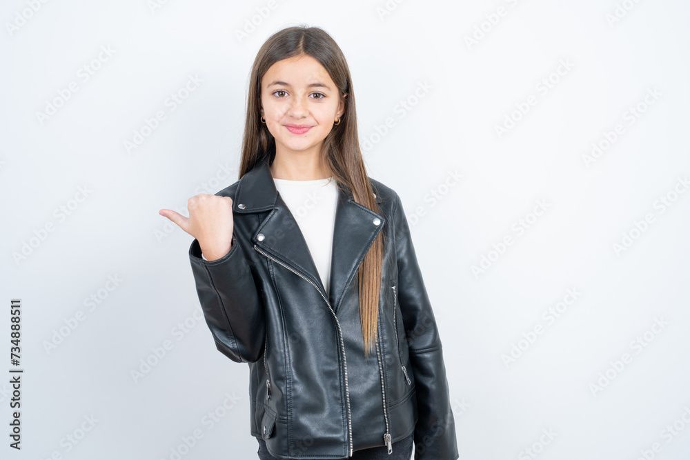 beautiful kid girl wearing biker jacket over white background points away and gives advice demonstrates advertisement beautiful kid girl wearing biker jacket over white background points away and gives advice demonstrates advertisement