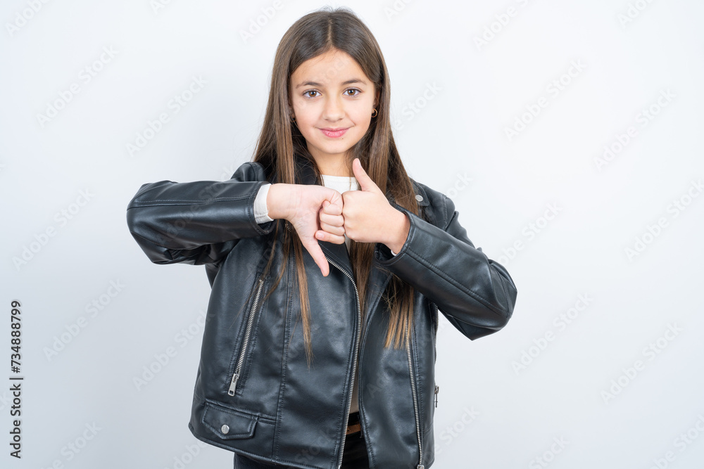 beautiful kid girl wearing biker jacket over white background showing thumb up down sign beautiful kid girl wearing biker jacket over white background showing thumb up down sign