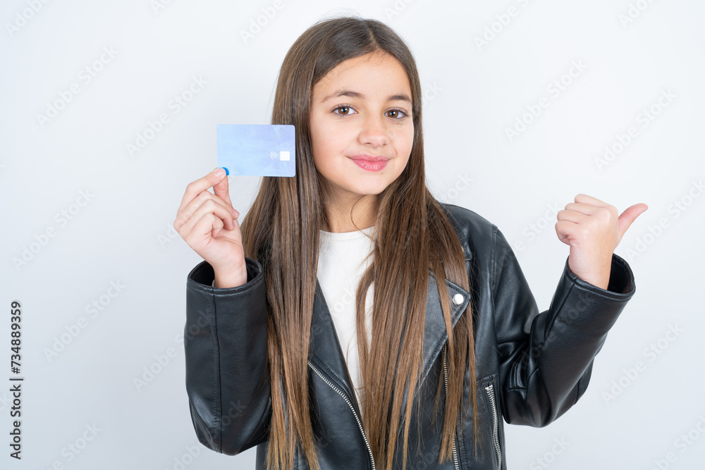 Young beautiful teen girl wearing biker jacket hold credit card point empty space Young beautiful teen girl wearing biker jacket hold credit card point empty space