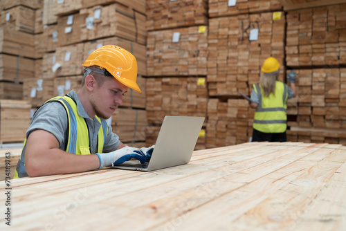 Male warehouse worker working with laptop computer in lumber storage warehouse. Worker working in timber storage warehouse. Manufacturing and warehouse concept