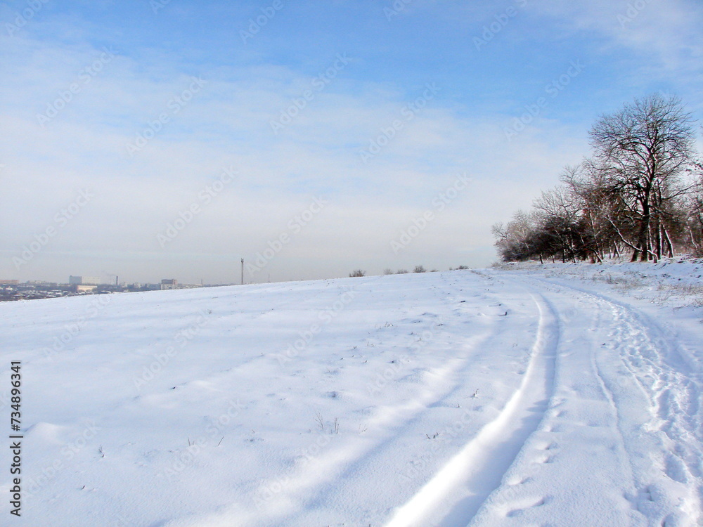An amazing natural picture of the combination of the bright white color of the snowy steppe and the sunny white-blue sky in the frosty winter.