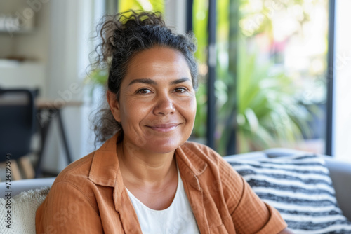 A woman sitting on a couch, smiling directly at the camera.