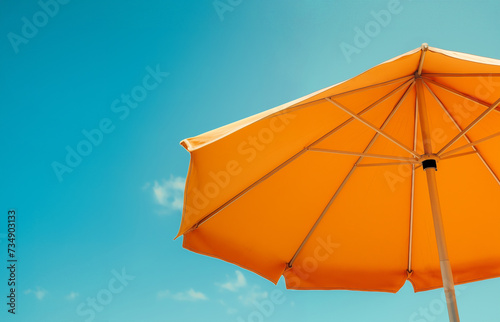 A bright beach umbrella against the backdrop of a clear blue sky. Summer background, bottom view, copy space.