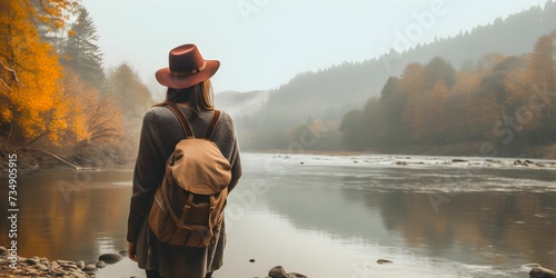 AI-generated illustration of a young woman standing on a rocky river shore in autumn