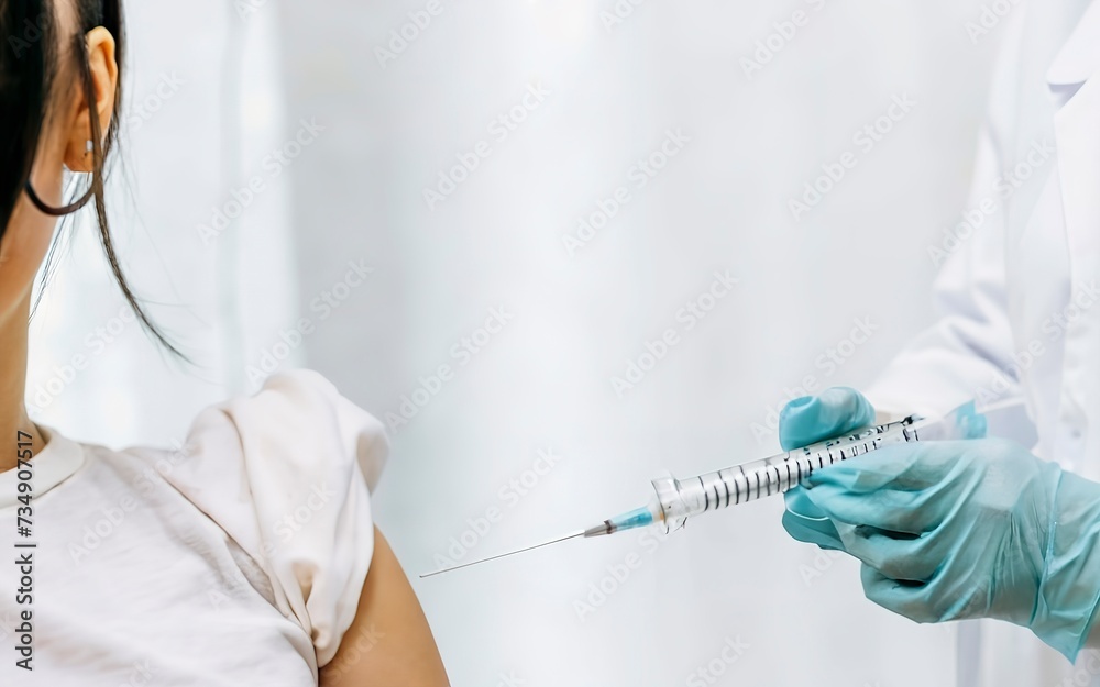 hand of a medical worker with an injection syringe prepares to be vaccinated in the shoulder of a young woman - obrazy, fototapety, plakaty 