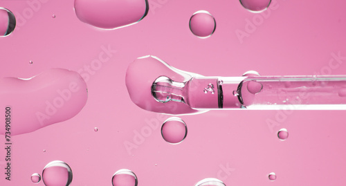Cosmetic dropper with serum, beauty cosmetics dripping, on pink background. Macro shot. Serum, peptides, beauty and health care products. Glass pipette with liquid, close up. Top view. Skin care 
