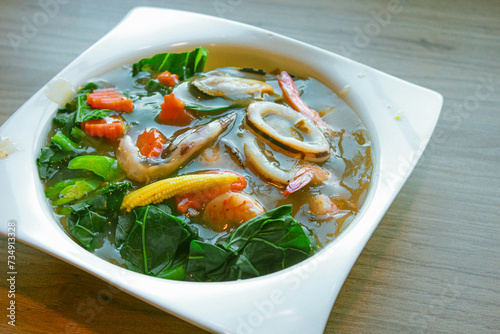 Wide Rice Noodles with Seafood in Gravy Sauce, or what we call Rad-Na Taley, served on a white plate in an Asian restaurant. photo