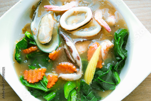 Wide Rice Noodles with Seafood in Gravy Sauce, or what we call Rad-Na Taley, served on a white plate in an Asian restaurant. photo