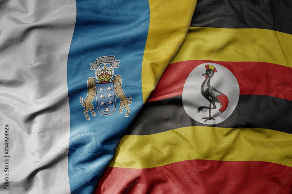 Fototapeta premium big waving national colorful flag of uganda and national flag of canary islands .