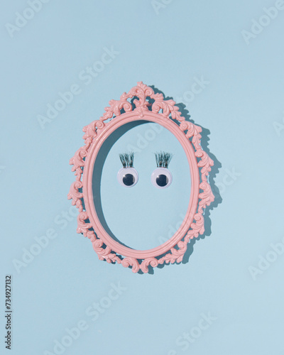 Eyes and false eyelashes, minimal female face in a retro oval frame, pastel blue background.
