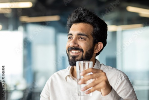 Photography Close-up photo of a young man, an Indian businessman sitting in the office and h