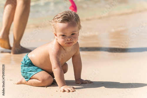 Toddler with down syndrome exploring the beach on a sunny day photo