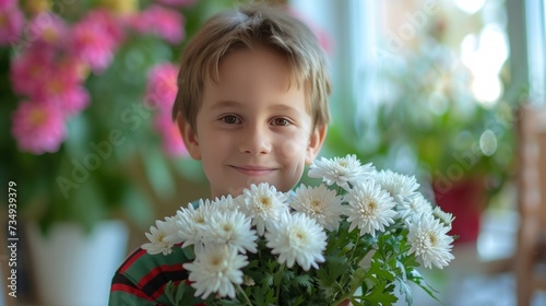A 10-year-old boy holds in his hands a bouquet of chrysanthemums that he brought for his mother