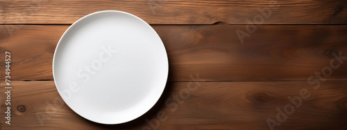 An empty white plate atop a rustic wooden table, viewed from above. This simple yet inviting image captures the rustic charm of farmhouse dining, making it perfect for food blog headers and restaurant