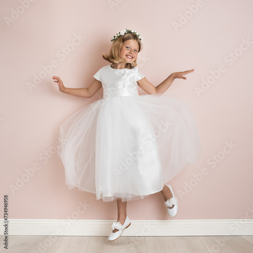 blonde girl 9 years old in a white festive dress on a pale pink background, dress for a wedding, first communion, birthday, celebration