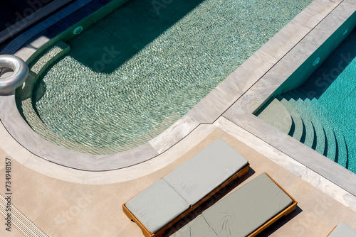 Top view of swimming pool with sunbeds. Summer backround.