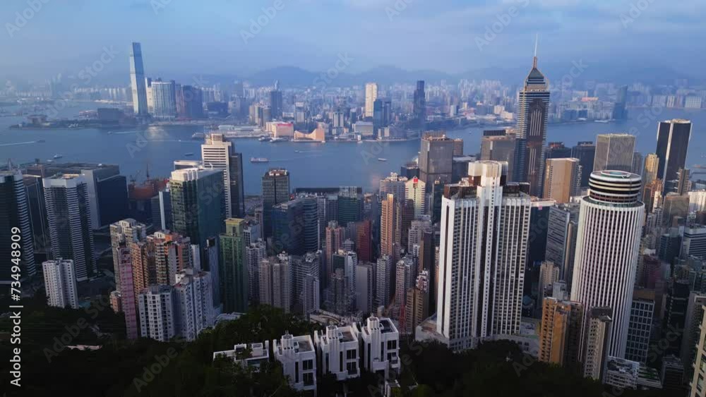 Hong Kong, China: impressive skyscrapers and calm harbor with moving boats filmed by drone with mountains on the background. Aerial scenery of coastal town with high buildings of business downtown