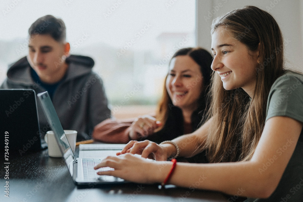 Smiling girl using laptop by mother and brother at dining table Smiling girl using laptop by mother and brother at dining table
