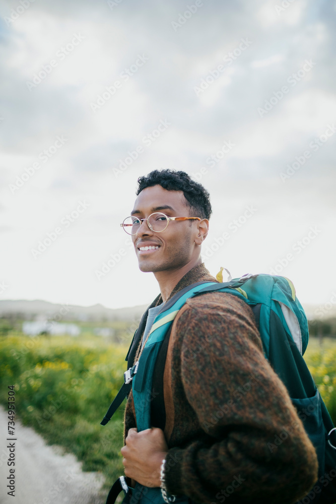 Side view portrait of man with backpack hiking under sky