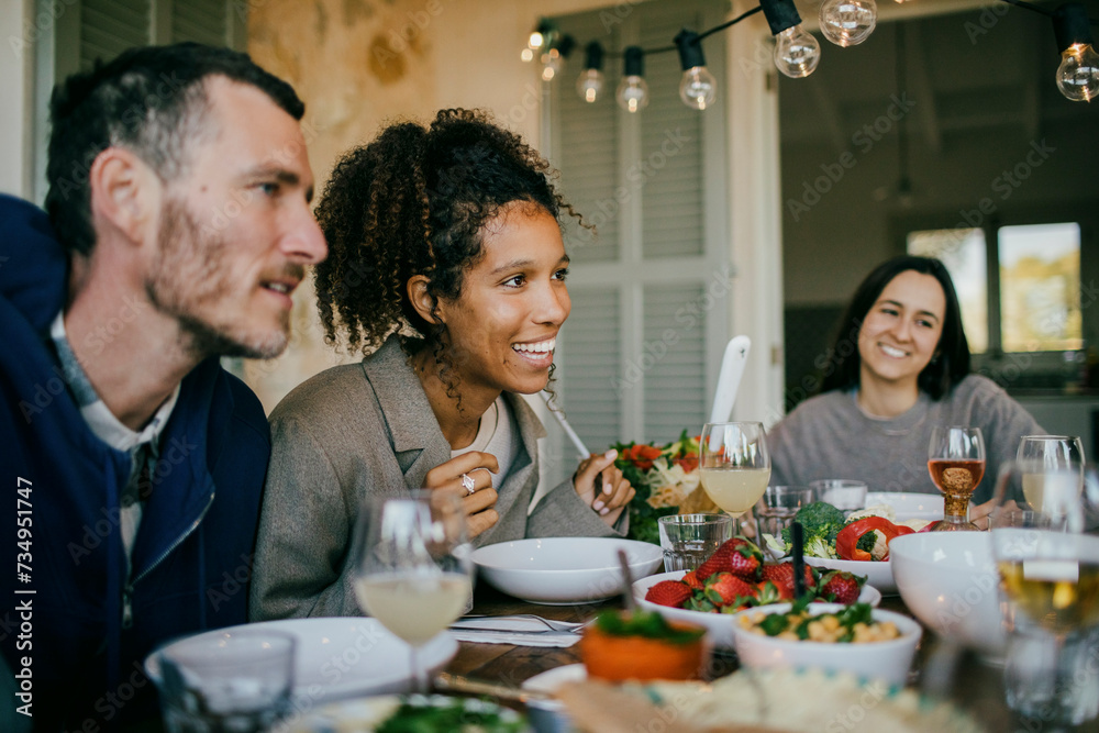 Smiling woman sitting with friends at dining table for dinner party Smiling woman sitting with friends at dining table for dinner party