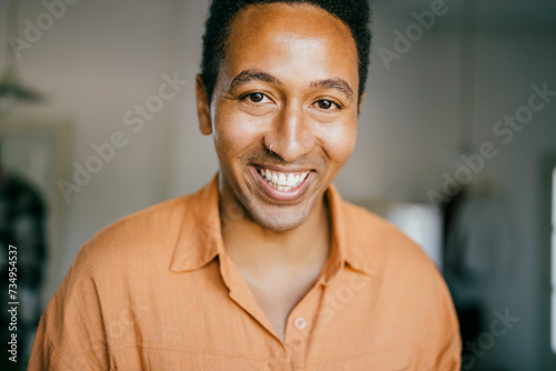 Portrait of smiling man with nose ring at home photo