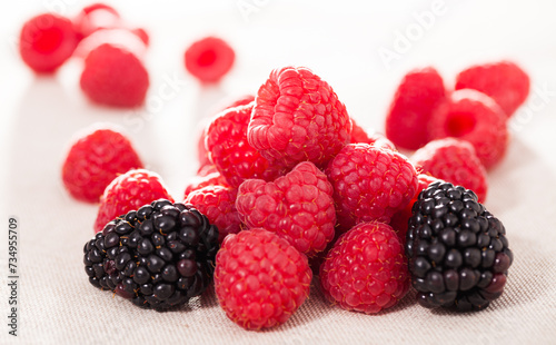 Handful of fresh raspberry and blackberry berries on white background