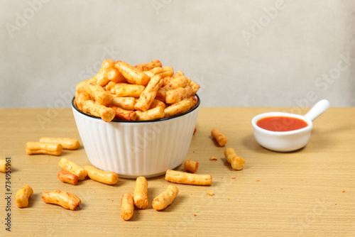 kerupuk tongkol pedas or crackers made from tuna with a spicy taste. or spicy stick snacks in a white bowl. photo