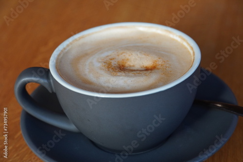 Close up of grey cup of cappuccino with nice foam and brown sugar on the top on wooden background
