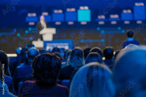 Audience attentively listening to a keynote speaker at a professional event or business conference. photo