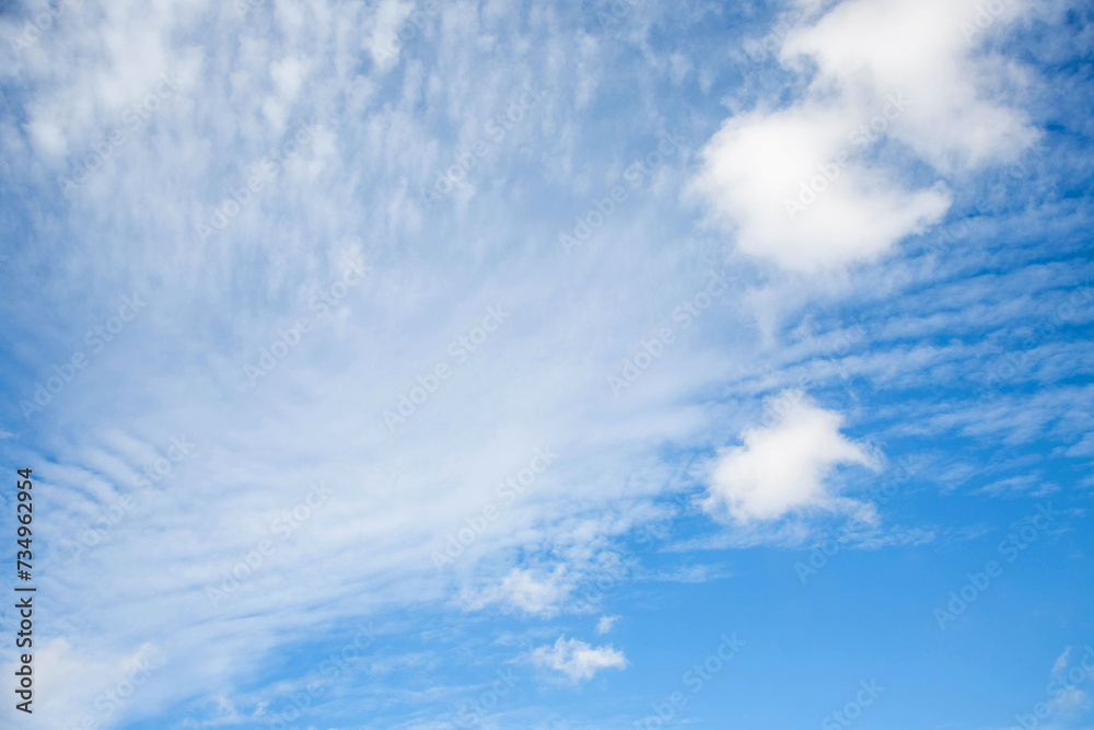 White cloudy ripples with small clouds on a bright blue sky. Background bright calm sky. White cloudy ripples with small clouds on a bright blue sky. Background bright calm sky.